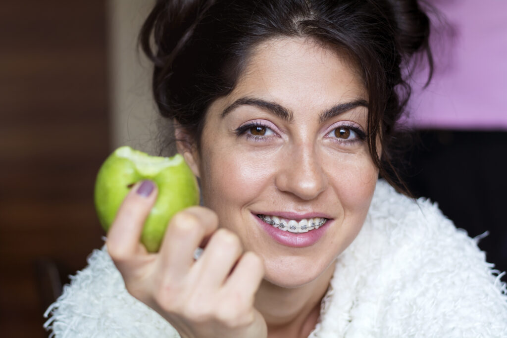 Una mujer con brackets come una manzana