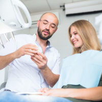 Un dentista muestra un yeso dental a su paciente