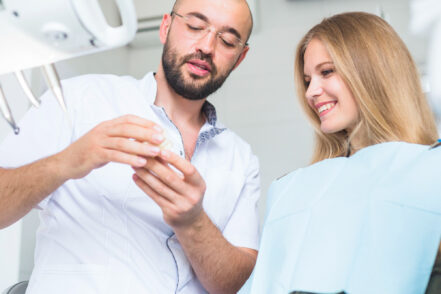 Un dentista muestra un yeso dental a su paciente