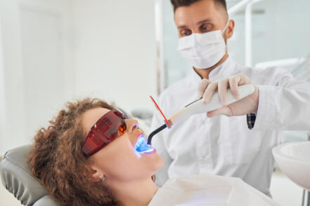 Un dentista aplica luz ultravioleta a los dientes de un paciente