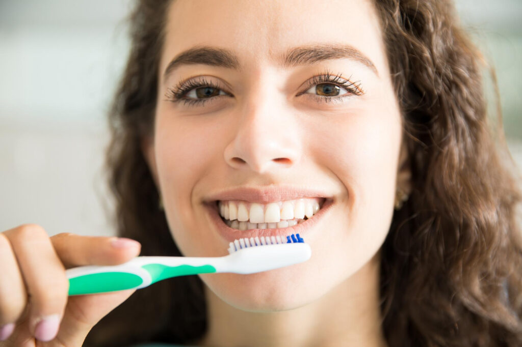 Una mujer se está cepillando los dientes
