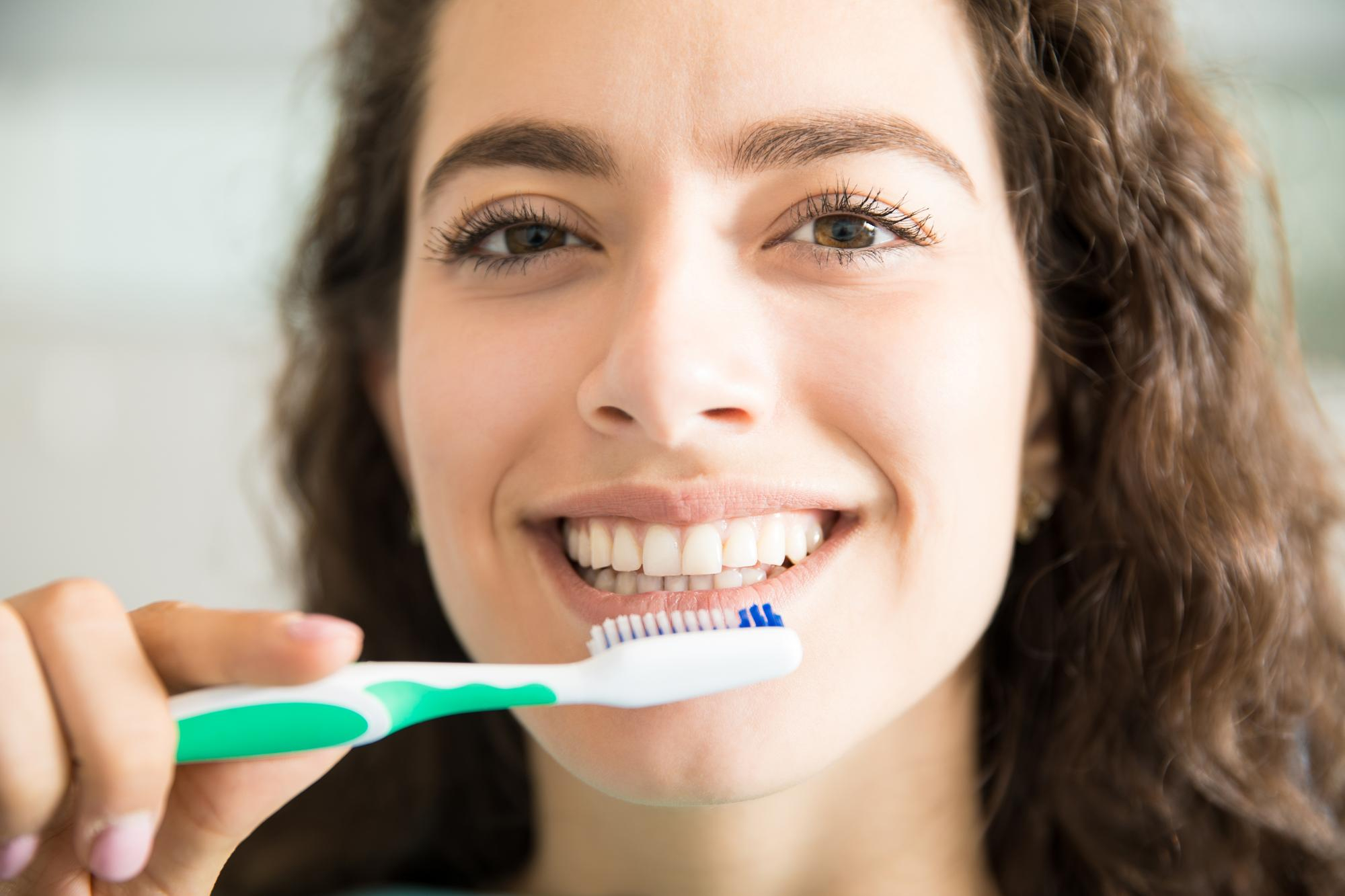 Una mujer se está cepillando los dientes